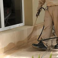 General pest control technician spraying exterior perimeter around a home in Tulsa, OK