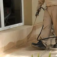 General pest control technician spraying exterior perimeter around a home in Tulsa, OK