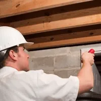 Termite inspection technician checking a basement wall and framing for termite activity in Tulsa, OK